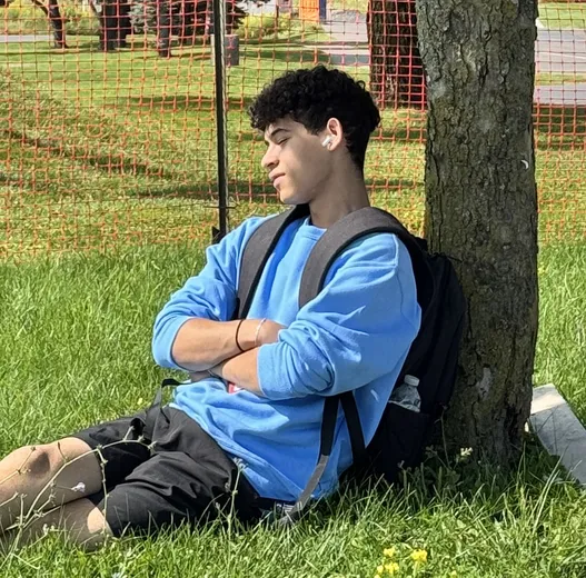 Jared sitting against a tree on the grass