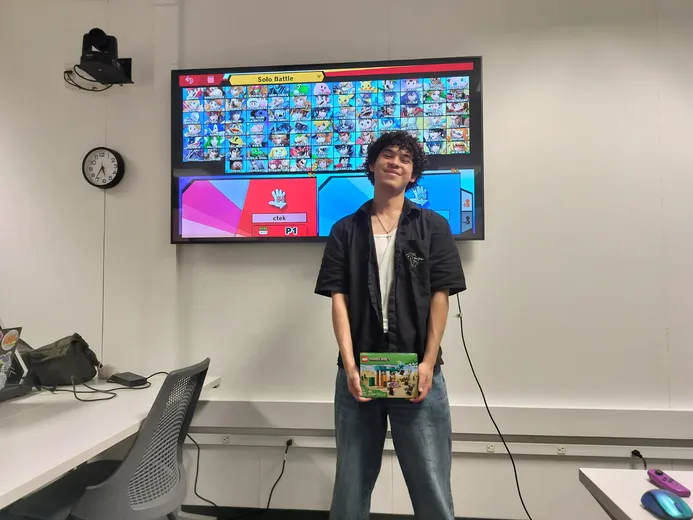 Jared holding up a prize in front of a game on a TV